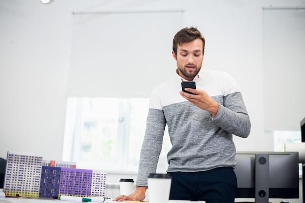 Un retrato de un joven arquitecto hablando con alguien por teléfono usando el modo de altavoz