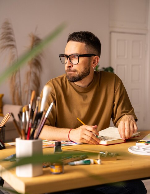 Foto retrato de un joven artista dibujando sentado en la mesa