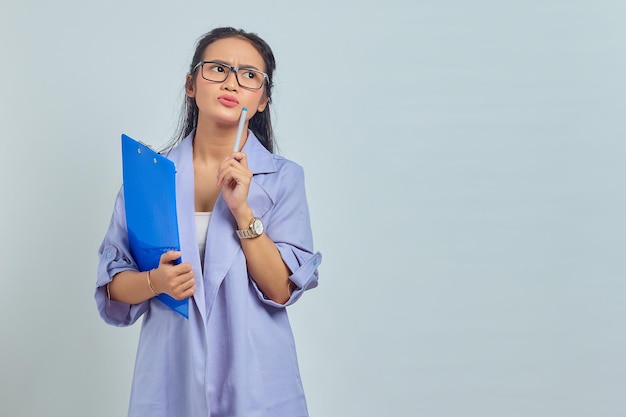 Retrato de una joven asiática concentrada escribiendo notas planeando crear una estrategia sobre un fondo morado