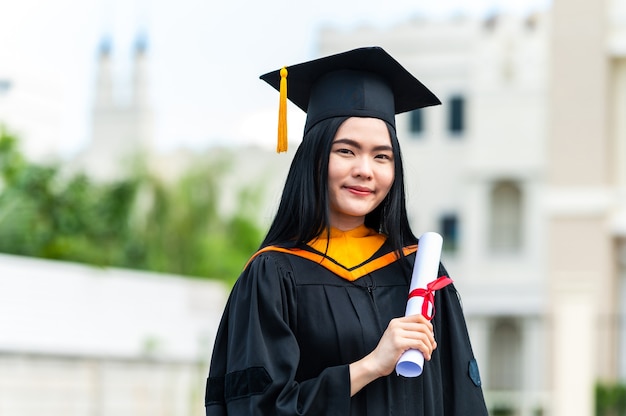 Retrato de joven asiática con diploma de graduación al aire libre