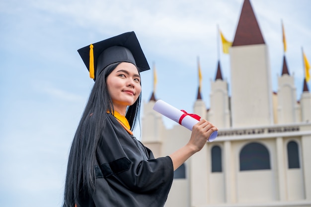 Retrato de joven asiática con diploma de graduación al aire libre