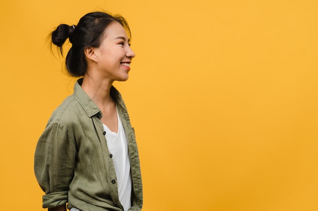 Retrato de joven asiática con expresión positiva, sonrisa amplia, vestida con ropa casual sobre pared amarilla. Feliz adorable mujer alegre se regocija con el éxito. Concepto de expresión facial.