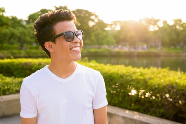 Retrato de joven asiática con gafas de sol mientras se relaja en el parque en Bangkok, Tailandia