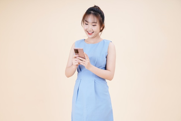 Retrato de una joven asiática hermosa y alegre mujer usando un teléfono inteligente aislado en el fondo