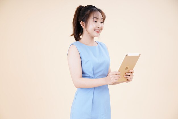 Retrato de una joven asiática hermosa y alegre mujer usando un teléfono inteligente aislado en el fondo