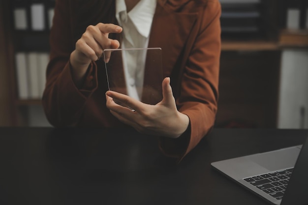 Retrato de una joven asiática independiente está trabajando en su trabajo en una tableta de computadora en una oficina moderna. Haciendo un informe de análisis contable. Datos de inversión inmobiliaria. Concepto de sistemas financieros y fiscales.