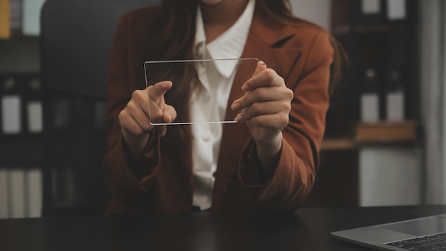 Retrato de una joven asiática independiente está trabajando en su trabajo en una tableta de computadora en una oficina moderna. Haciendo un informe de análisis contable. Datos de inversión inmobiliaria. Concepto de sistemas financieros y fiscales.