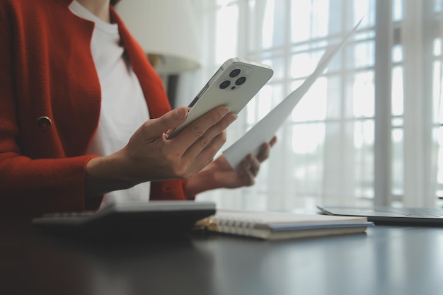 Retrato de una joven asiática independiente está trabajando en su trabajo en una tableta de computadora en una oficina moderna. Haciendo un informe de análisis contable. Datos de inversión inmobiliaria. Concepto de sistemas financieros y fiscales.