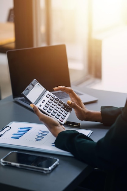 Retrato de una joven asiática independiente está trabajando en su trabajo en una tableta de computadora en una oficina moderna. Haciendo un informe de análisis contable. Datos de inversión inmobiliaria. Concepto de sistemas financieros y fiscales.