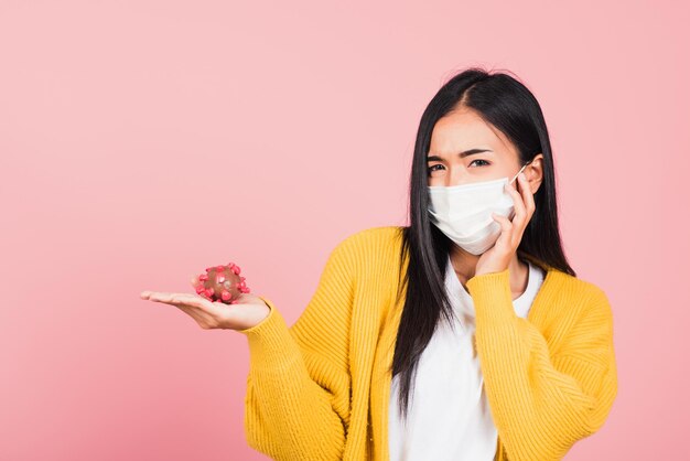 Retrato de una joven asiática con mascarilla protectora que sostiene la hebra de ADN de la instrucción genética del coronavirus (COVID-19, 2019-ncov), nueva mutación del ARN de la cepa, toma de estudio aislada en el fondo rosa