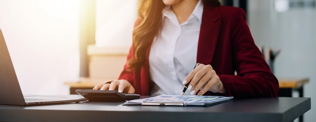 Retrato de una joven asiática que trabaja como freelancer en una tableta de computadora en una oficina moderna haciendo análisis de contabilidad, informes, datos de inversiones inmobiliarias, conceptos de sistemas financieros e fiscales.