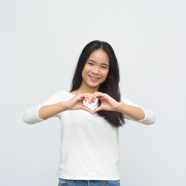 Retrato de joven asiática sonriendo con manos en forma de corazón