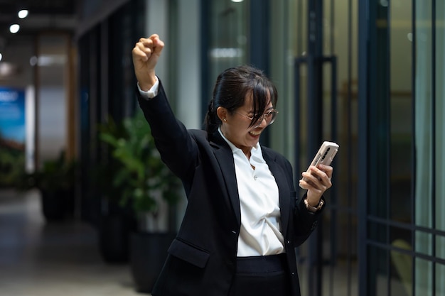 Retrato de una joven asiática con una sonrisa una mujer de negocios asiática feliz usando un teléfono móvil un lugar de trabajo de oficina moderno