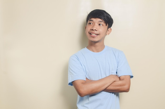 Retrato de un joven asiático con camiseta azul pensando en algo en un fondo aislado