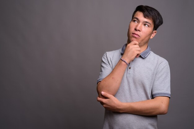 Retrato de joven asiático contra la pared gris