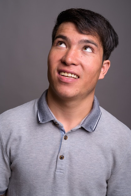 Retrato de joven asiático contra la pared gris