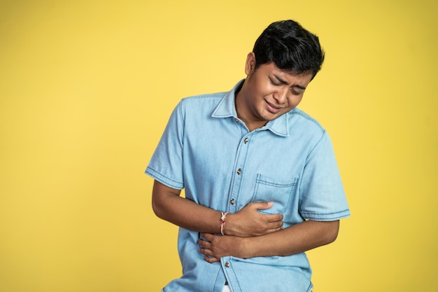 Retrato de un joven asiático con dolor de estómago en un fondo aislado