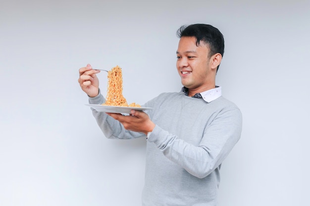 Retrato de un joven asiático feliz que disfruta de los fideos comiendo el concepto del almuerzo