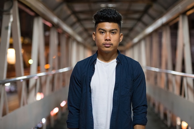 Retrato de joven asiático en la pasarela de la ciudad por la noche