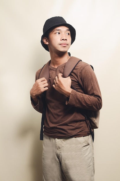 Retrato de un joven asiático pensante que lleva una mochila aislada en el fondo
