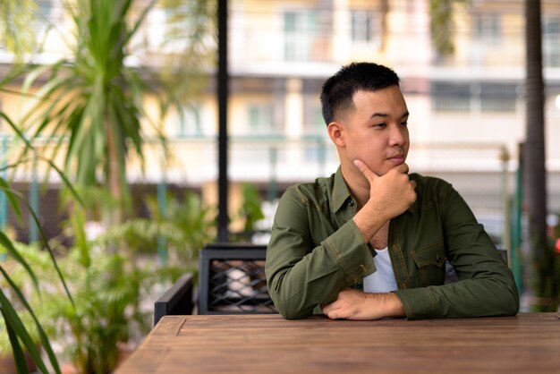 Retrato de joven asiático relajándose en la cafetería.