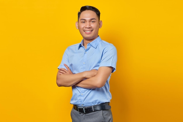 Retrato de un joven asiático sonriente con anteojos cogidos de la mano y se siente optimista aislado en el concepto de empresario y emprendedor de fondo amarillo