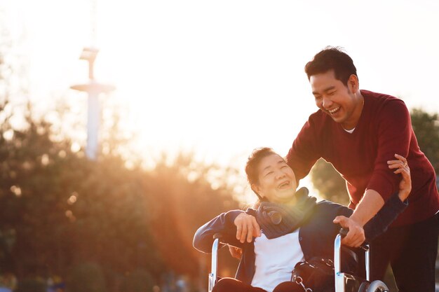 Retrato de un joven asiático sonriente disfrutando de un tiempo dulce y tierno al aire libre con una madre mayor