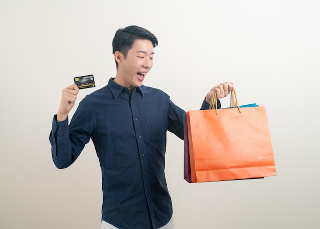 Retrato joven asiático con tarjeta de crédito y bolsa de compras