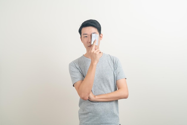 Retrato joven asiático con tarjeta de crédito sobre fondo blanco.