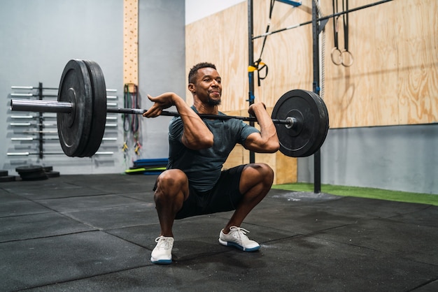 Retrato de joven atleta crossfit haciendo ejercicio con una barra. Crossfit, deporte y concepto de estilo de vida saludable.