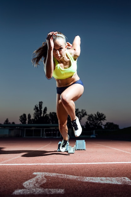 Retrato de joven atleta lanzando desde la línea de salida en una carrera.