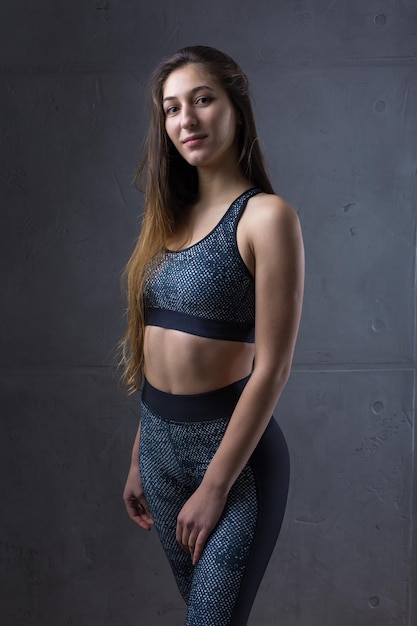Retrato de una joven atlética delgada contra una pared de hormigón en el interior de un apartamento de moda