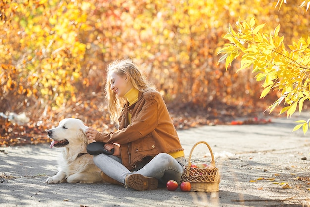 Retrato de joven atractiva chica rubia con perro. Dueño de una mascota. Golden retriever y su dueño en otoño.