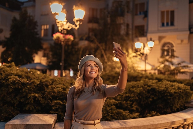 Retrato de una joven atractiva en la ciudad tomando un selfie con su teléfono móvil