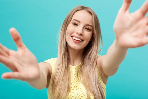 Retrato de joven atractiva estirando sus brazos, quiere abrazarte.