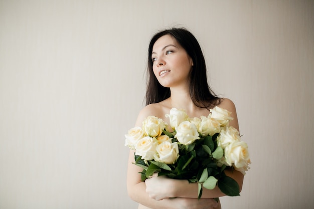 Retrato de una joven atractiva con ramo de rosas.