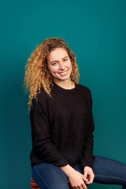 Retrato de joven atractiva sonriente alegre alegre rizado jengibre niña vestida con suéter negro.