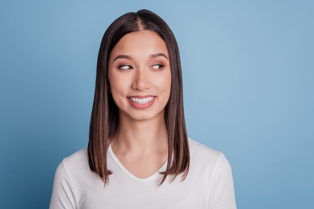 Retrato de joven atractiva sonriente soñadora curiosa mirada espacio vacío interesado aislado sobre fondo de color azul