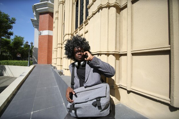 Retrato de un joven y atractivo modelo afroamericano con estilo posando con ropa informal en un fondo neutro que se ve sexy con el pelo afro. En Gente Juventud Concepto de belleza y moda.