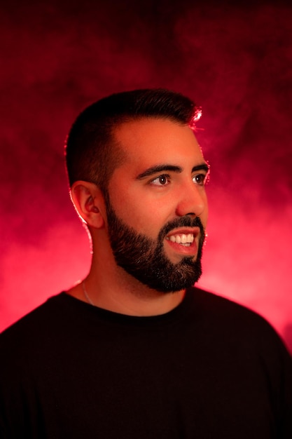 Retrato de un joven con barba sobre un fondo rojo y negro con humo