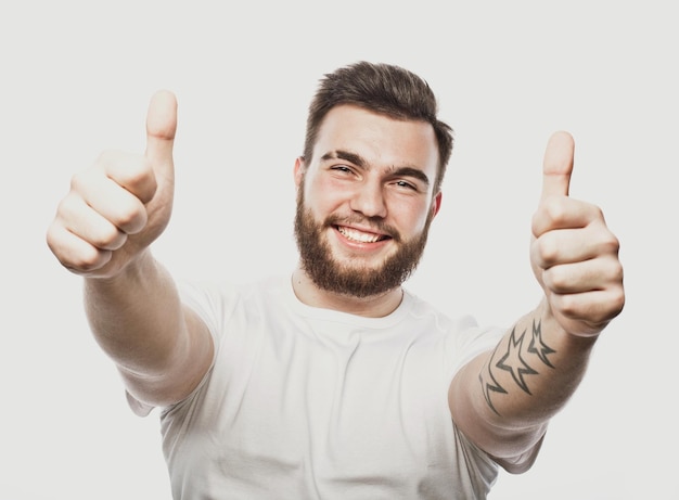 Retrato de un joven barbudo alegre que muestra un gesto correcto aislado en el fondo blanco