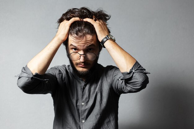 Retrato de joven barbudo con cabello despeinado y gafas