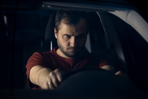 Retrato de un joven barbudo confiado agarrando un volante con sus manos