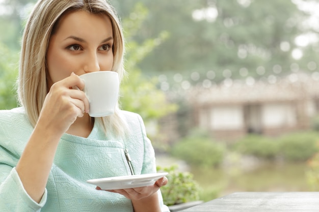 Retrato de una joven bebiendo su café de la mañana durante un desayuno en la cafetería