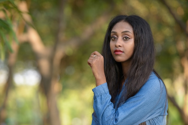 Retrato de joven bella mujer africana relajándose en el parque al aire libre