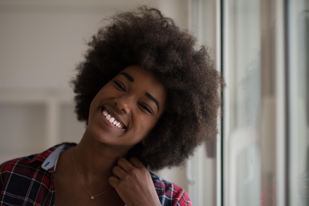 retrato de una joven y bella mujer afroamericana con el pelo rizado cerca de la ventana