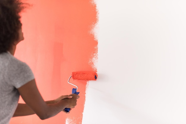 retrato de una joven y bella mujer afroamericana pintando una pared en su nuevo apartamento