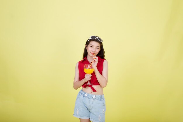 Retrato de una joven y bella mujer asiática bebiendo jugo de naranja