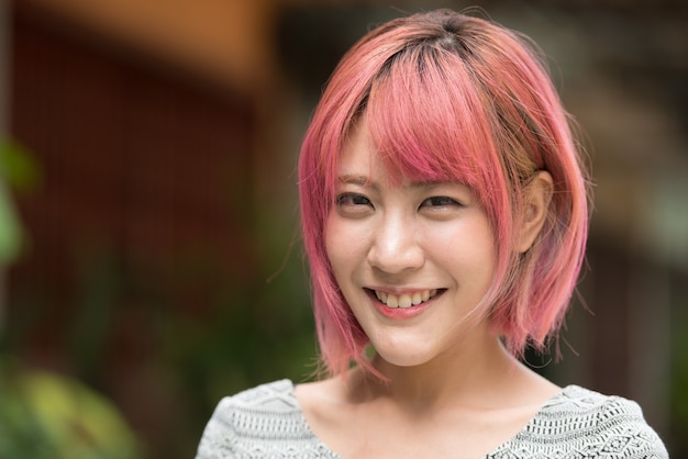 Retrato de joven bella mujer asiática con cabello rosado en las calles al aire libre