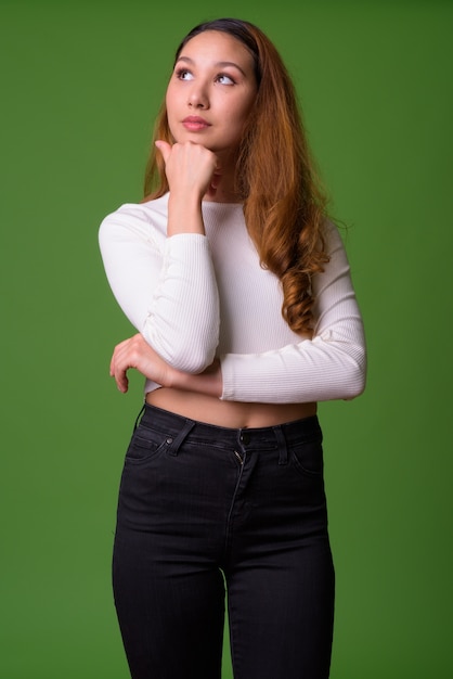 Retrato de joven bella mujer asiática contra la pared verde